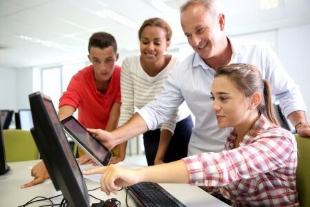 Teacher Comparing Tablet Device and Desktop Monitor